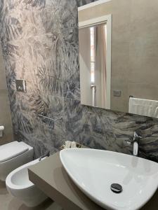 ein Badezimmer mit einem Waschbecken, einem WC und einem Spiegel in der Unterkunft Gemini rooms in Crotone
