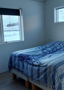 uma cama num quarto branco com uma janela em Tungukot sumarhús em Akureyri