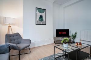 ein Wohnzimmer mit einem Stuhl und einem TV in der Unterkunft Anfield House - Liverpool Retreat 7 Bedroom Home in Liverpool