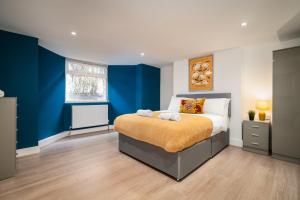 Schlafzimmer mit einem Bett mit blauen Wänden und einem Fenster in der Unterkunft Anfield House - Liverpool Retreat 7 Bedroom Home in Liverpool