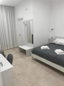 ein weißes Schlafzimmer mit einem Bett und einem Spiegel in der Unterkunft Gemini rooms in Crotone