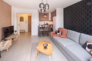 ein Wohnzimmer mit einem Sofa und einem Tisch in der Unterkunft L'excellence-Parking privé-8min Aéroport-NBSimmo in Lingolsheim