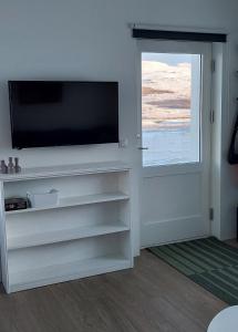 uma sala de estar com uma televisão de ecrã plano e uma janela em Tungukot sumarhús em Akureyri
