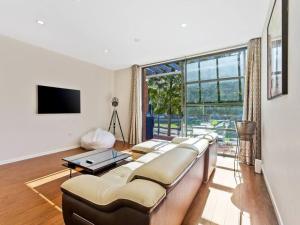 uma sala de estar com um sofá e uma grande janela em Sleek Modern Pad next to Spark Arena Free Parking em Auckland
