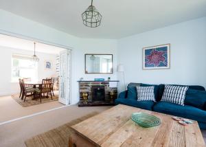 a living room with a blue couch and a wooden table at Lundy House in Port Isaac