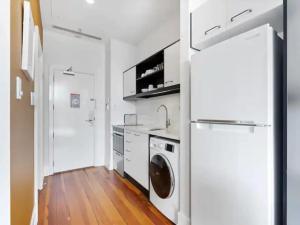 una cocina blanca con lavadora y secadora. en Lovely Bright Apt with Pool and Gym by Zodiak Stays, en Auckland