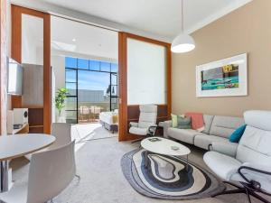 una sala de estar con un sofá y una mesa en Lovely Bright Apt with Pool and Gym by Zodiak Stays, en Auckland