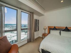オークランドにあるSpacious 1BR Apt Parking, Gym ,Pool by Zodiak Staysのベッドと大きな窓のある寝室 +9枚の写真