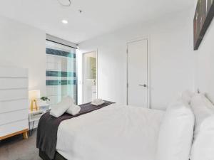 a white bedroom with a white bed and a window at Two bedroom apartment - large balcony central in Auckland