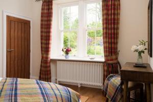 1 dormitorio con 1 cama y una ventana con cortinas en Pentland Cottage, en Norham