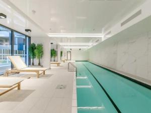 a swimming pool in a large white room with a swimming pool at Cosy Two Bedroom Apartment with Balcony Pool and Gym in Auckland