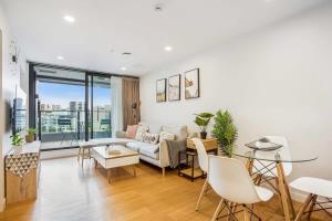 a living room with a couch and a table at Cosy Two Bedroom Apartment with Balcony Pool and Gym in Auckland