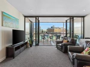 a living room with a couch and a flat screen tv at Lovely view apartment - free parking, pool and gym in Auckland