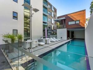 a swimming pool with white chairs next to a building at Lovely view apartment - free parking, pool and gym in Auckland