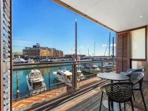 a balcony with a table and chairs and a view of a harbor at Lovely view apartment - free parking, pool and gym in Auckland