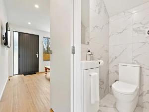 a white bathroom with a toilet and a sink at Stunning Three Bedroom Townhouse with Free Parking in Auckland