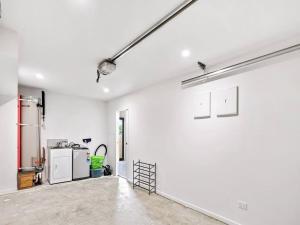 an empty room with a white wall and a kitchen at Stunning Three Bedroom Townhouse with Free Parking in Auckland