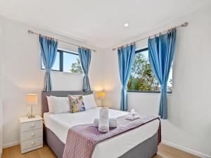 1 dormitorio con 1 cama grande y cortinas azules en Gorgeous Three Bedroom Home with Free Parking, en Auckland