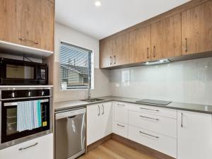 a kitchen with white cabinets and stainless steel appliances at Brand New Three Bedroom Townhouse with Garage in Auckland