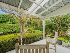 a porch with a white pergola and a bench at Cheerful 1 Bedroom Home with Free Parking in Auckland