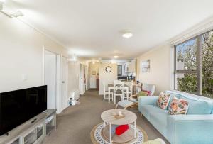 uma sala de estar com um sofá azul e uma televisão em Lovely 2-Bedroom Apartment with Free Parking em Auckland
