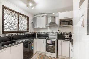 uma cozinha com armários brancos e uma janela em Lovely 2-Bedroom Apartment with Free Parking em Auckland
