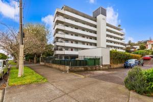 um grande edifício branco com carros estacionados num parque de estacionamento em Lovely 2-Bedroom Apartment with Free Parking em Auckland