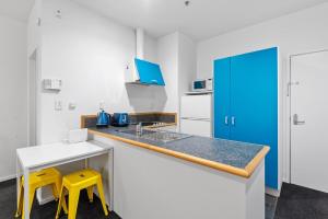 cocina con encimera y 2 taburetes amarillos en Cosy and central studio, en Auckland