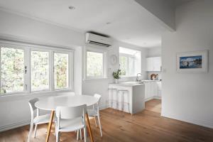 a white kitchen with a white table and chairs at Three-Bedroom Grey Lynn Villa in Auckland