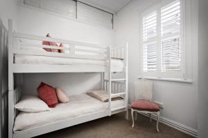 a bedroom with two bunk beds and a chair at Three-Bedroom Grey Lynn Villa in Auckland