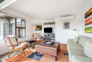 a living room with a couch and a table at Stylish and serene living in Kohimarama in Auckland