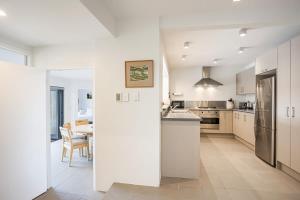 a kitchen with white cabinets and a dining room with a table at Stylish and serene living in Kohimarama in Auckland
