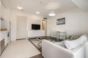Sala de estar blanca con sofá blanco y mesa en Bright & modern Auckland CBD apartment, en Auckland