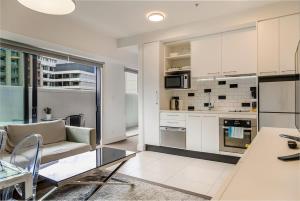 cocina y sala de estar con sofá y mesa en Bright & modern Auckland CBD apartment, en Auckland