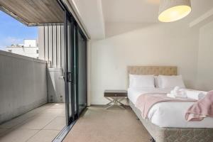 1 dormitorio con cama y ventana grande en Bright & modern Auckland CBD apartment, en Auckland