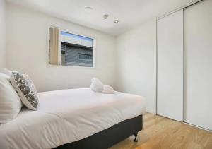a bedroom with a large white bed and a window at Central two-bedroom apartment close to Spark Arena in Auckland