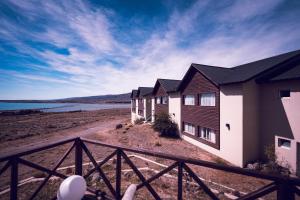 a house with a fence next to a body of water at Edenia Hotel & Nature in El Calafate