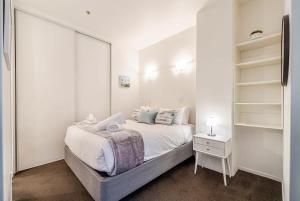 um quarto branco com uma cama e um espelho em Retro style on Queen Street em Auckland