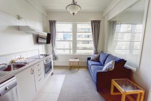 a living room with a blue couch and a kitchen at Central Auckland 1-bedroom apartment in Auckland