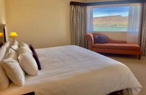 a bedroom with a large bed with a chair and a window at Edenia Hotel & Nature in El Calafate