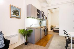 a kitchen with white cabinets and a table with a plant at Cosy Queen St 1-BR apartment in Auckland