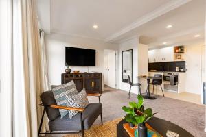 een woonkamer met een bank, een tv en een tafel bij Immaculate city-fringe apartment in Auckland