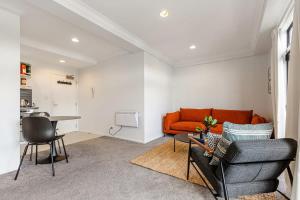 a living room with an orange couch and a table at Immaculate city-fringe apartment in Auckland