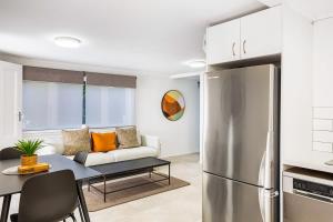 Freshly renovated Grey Lynn 3BR unit في أوكلاند: مطبخ وغرفة معيشة مع أريكة وثلاجة