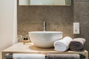 ein Badezimmer mit einem Waschbecken und Handtüchern auf der Theke in der Unterkunft Zum Hirschen Boutique Hotel Val di Non in Unsere Liebe Frau im Walde