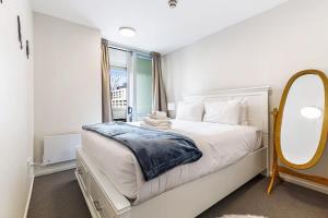a white bedroom with a large bed and a mirror at Cosy Central 1BR with Balcony in Auckland