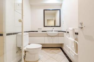a white bathroom with a toilet and a sink at Cosy studio on Queen Street in Auckland