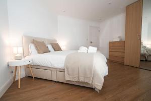 a white bedroom with a large bed and a dresser at Spacious 1 Bed with free parking in Hounslow in Hounslow