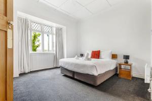 a white bedroom with a bed and a window at Character-Filled Home w Parking in Auckland
