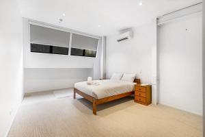 - une chambre blanche avec un lit et 2 fenêtres dans l'établissement Contemporary 1BR Queen Street Retreat, à Auckland